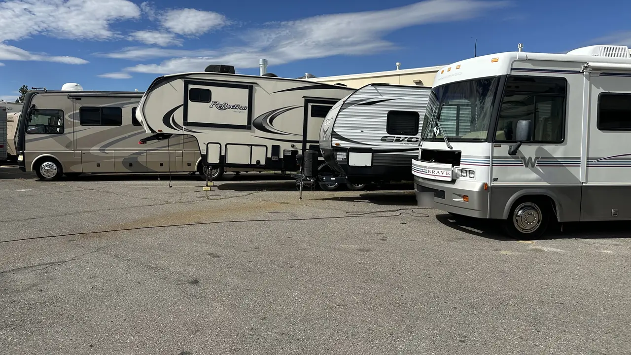 A motorhome, a fifth wheel, a travel trailer and a Class A parked in a row in the shop yard